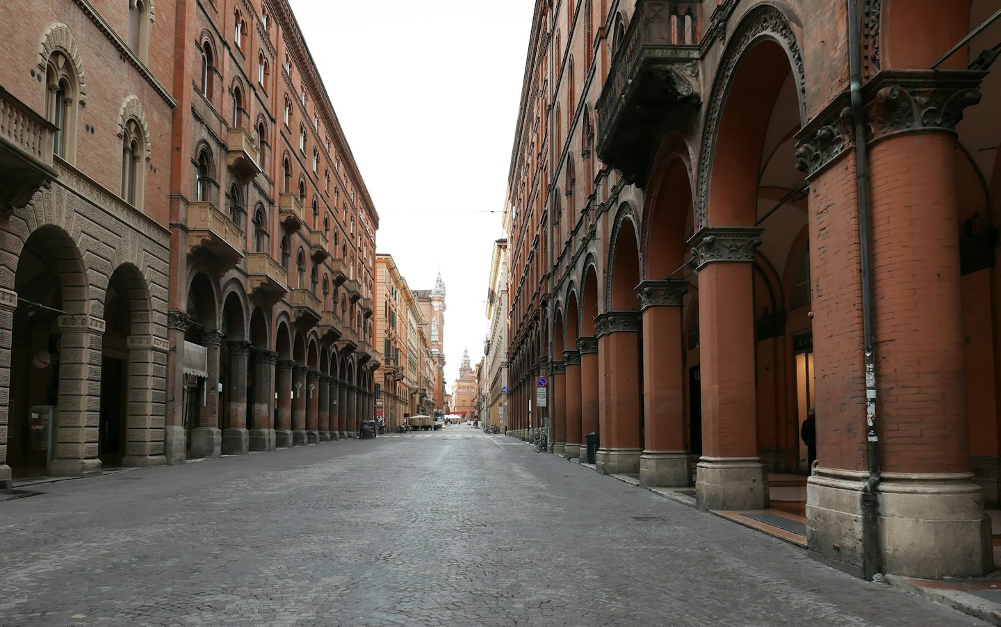 Una strada acciottolata vuota fiancheggiata da tradizionali edifici in mattoni italiani.