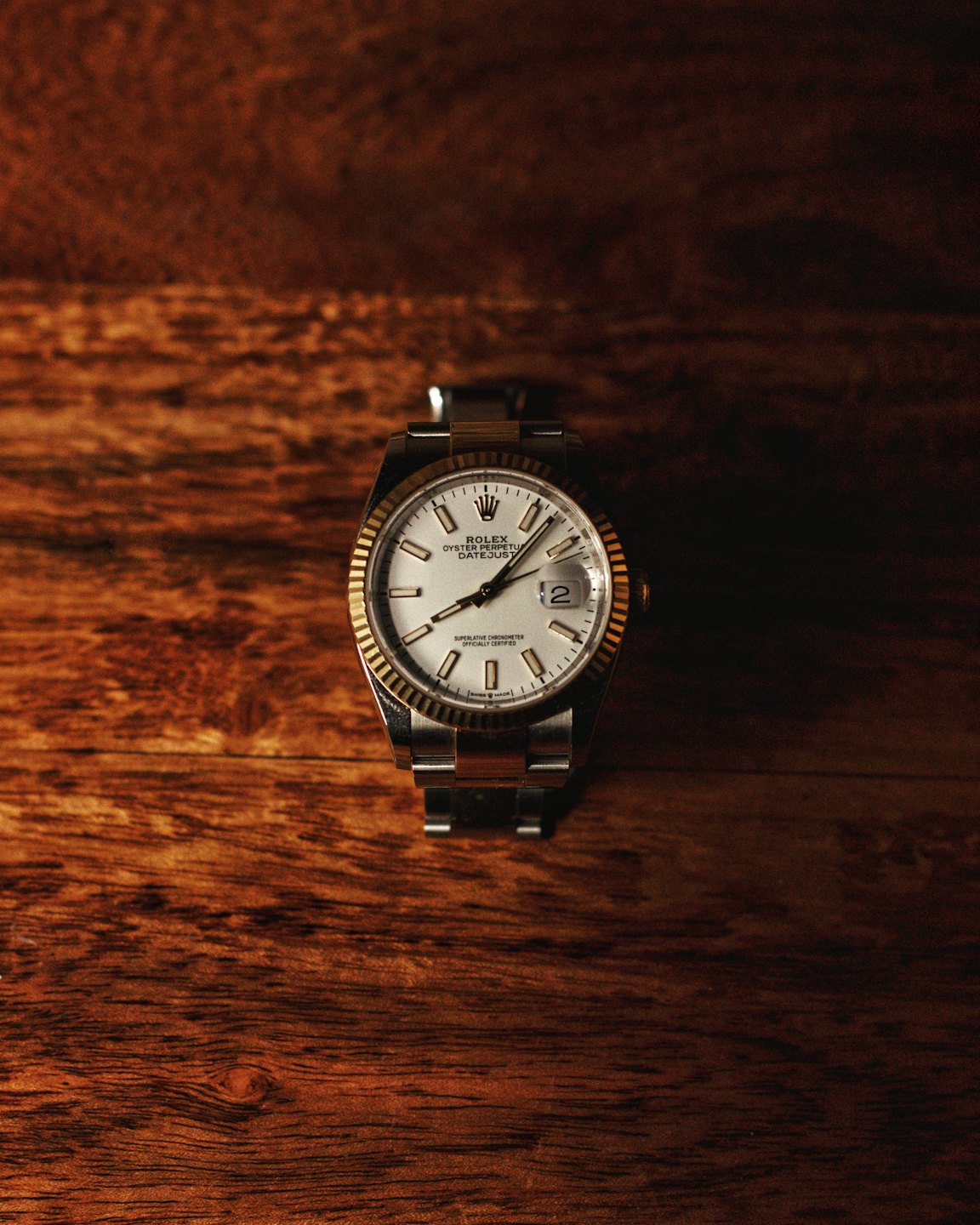 Orologio di lusso con lunetta in oro su legno scuro.