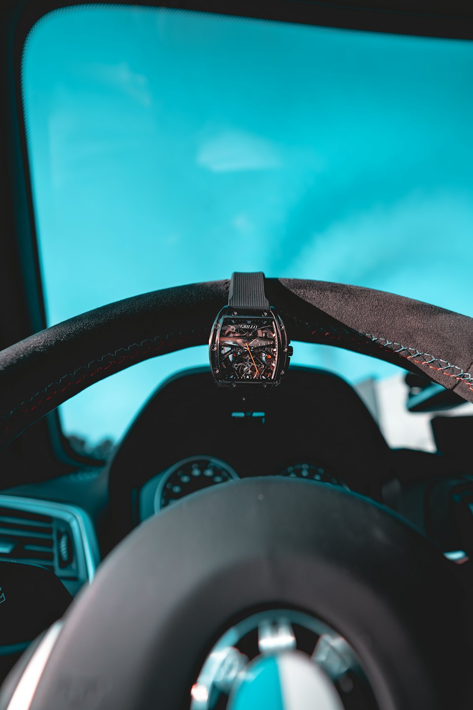Orologio scheletro appeso al volante di un'auto di lusso.